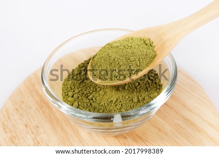 Bowl of green tea matcha powder in a wooden spoon on a white background 