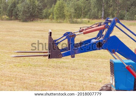 Attachments for a tractor, a fork for moving hay rolls. hay harvesting, seasonal work on the farm
