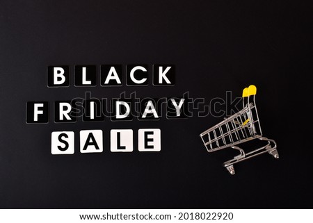 On a black background, the inscription Black Friday sale and a stroller from the supermarket. Flat layout, top view