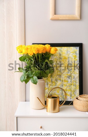 Vase with beautiful yellow roses on chest of drawers in interior of room