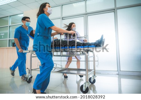 Emergency Department: Doctors, Nurses and Paramedics Run and Push Gurney  Stretcher with Seriously Injured Patient towards the Operating Room. Modern Hospital with Professional Staff. Royalty-Free Stock Photo #2018028392