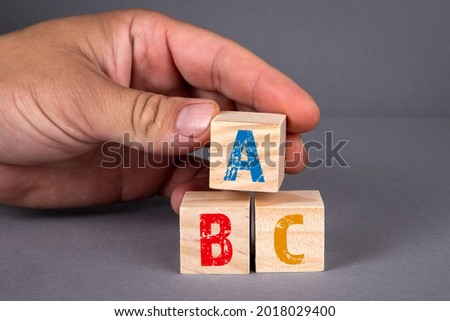 ABC alphabet wooden blocks and a man's hand on a gray background.