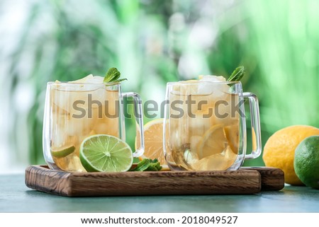 Cups of cold tea with mint and citrus fruits on table outdoors