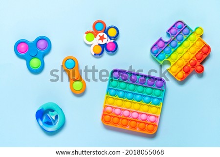 Colorful rainbow trendy Pop it and Simple dimple fidget different toys on blue background