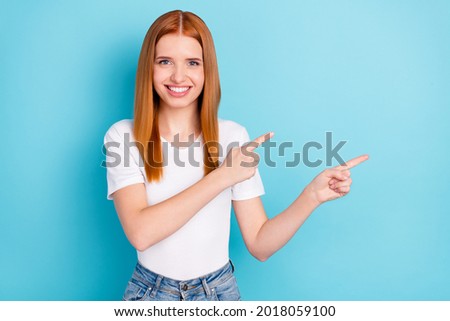 Photo of charming positive orange hair lady indicate fingers empty space offer isolated on blue color background