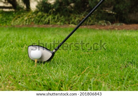 Golf ball on a tee with #3 wood, driver or pitching wedge