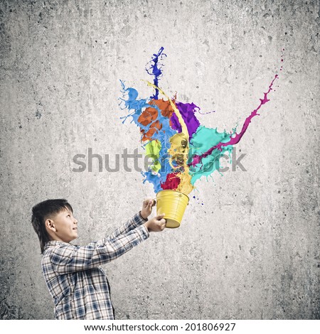 Cute boy splashing colorful paint from bucket