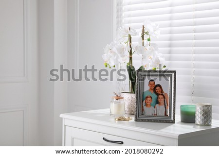 Framed family photo and orchid flower on drawer indoors, space for text