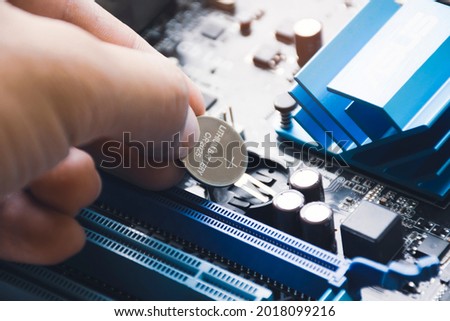 Computer mechanic install lithium battery CR2025 to CMOS backup battery slot on the computer motherboard Royalty-Free Stock Photo #2018099216