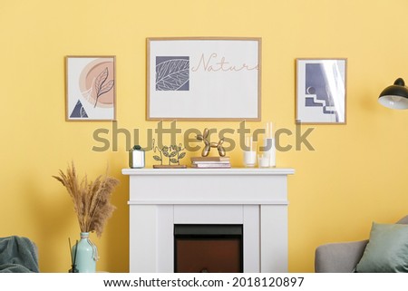 Fireplace with decor and pictures hanging on color wall