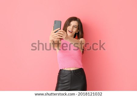 Stylish young woman taking selfie on color background