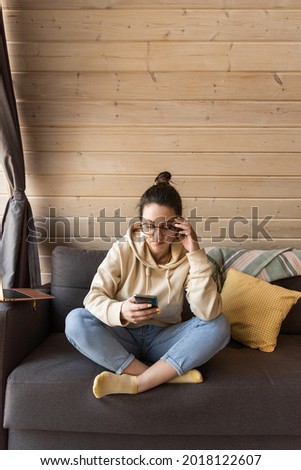 a girl during quarantine sits on the couch with a phone. The girl communicates on social networks during quarantine. High quality photo