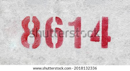 Red Number 8614 on the white wall. Spray paint. Number eight thousand six hundred and fourteen.
