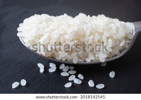 spoon full of white rice isolated on a black stone tile