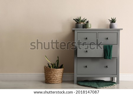 Room interior with grey chest of drawers near beige wall Royalty-Free Stock Photo #2018147087