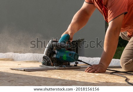 Plunge Cut Circular Saw when sawing OSB board

A man's hand held a plunge Cut Circular Saw OSB board using a guide rail while on the roof Royalty-Free Stock Photo #2018156156