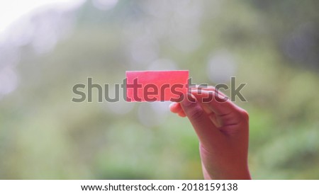 Pink note on bokeh background in the hands of a girl