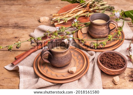 Hot natural chicory caffeine free drink in ceramic cups on a wooden table. Healthy alternative replacement for coffee, caffeine. Blue chicory flowers, fresh roots, copy space