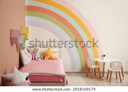 Cute child's room interior with beautiful rainbow painted on wall Royalty-Free Stock Photo #2018168174