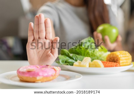 Diet, Dieting young asian woman or girl use hand push out, deny sweet donut and choose green apple, salad vegetables, eat food for good healthy, health when hungry. Close up female weight loss person. Royalty-Free Stock Photo #2018189174