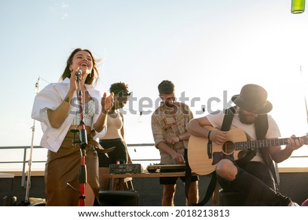 Modern music band of singer and guitarist performing at rooftop party or concert Royalty-Free Stock Photo #2018213813