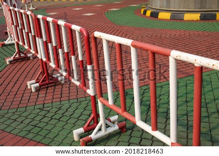 A lined up red and white striped iron barrier