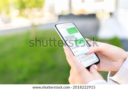 Texting sms with phone in city outdoor park. Woman sending text message with cellphone. Chatting on instant messaging app. Person using smartphone. Conversation and discussion with friend online. Royalty-Free Stock Photo #2018222915