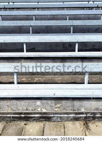 Light blue bench on a football soccer stadium. Outside sitting spot. Auditorium wooden seats on concrete stairs 