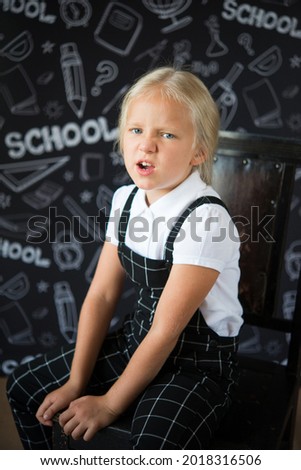 interesting little girl in school clothes against a school board with drawings on the theme of School. concept. Back to school.	