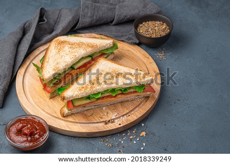 Two sandwiches with fried bread, ham, cheese and vegetables on a dark blue background. Side view, copy space