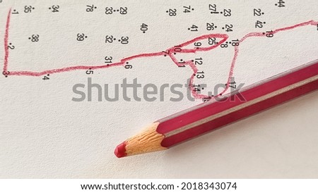  Connecting dots with numbers with a line with a red pencil. Drawing game. No straight lines. Step by step, small steps, patience concept. Close up. Royalty-Free Stock Photo #2018343074