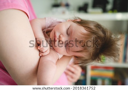 Close up on small caucasian baby sleeping in hands of her mother at home in bright summer day - Unknown woman holding her four months old baby daughter close up copy space motherhood concept