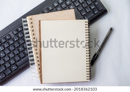 Two Plain Lined Spiral Notebooks With Pen And Keyboard On Table. Simple Notepads Ballpen Alongside Computer Keypad Placed On Top Of Desk. Royalty-Free Stock Photo #2018362103