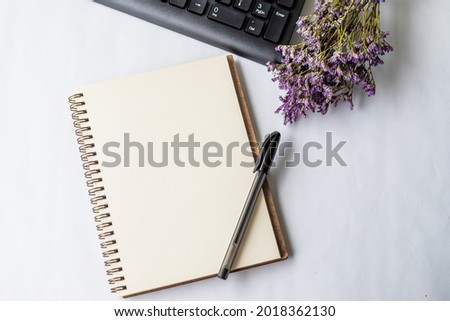 Empty Opened Journal With Pen Beside A Keyboard And A Flower On Top Of Desk, Blank Notepad With A Ballpen And A Floret Beside A Keypad Placed On A Table. Royalty-Free Stock Photo #2018362130