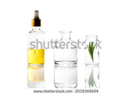 composition of three glass cosmetic bottles - with a pipette, transparent and with lavender leaves.