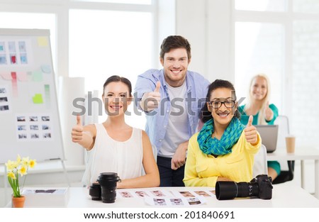 business, education, photography, office and startup concept - smiling creative team with photocamera in office showing thumbs up