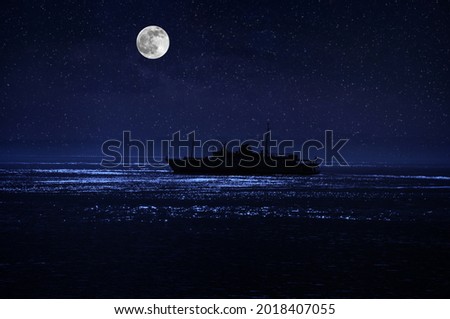 Beautiful night scene at sea. Dramatic moon over sea at night with silhouette of the ship