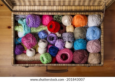 Aerial view of a messy pile of colorful balls of wool in an old suitcase