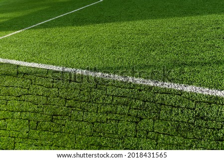 green artificial grass football or soccer field with white line and brick texture with sunlight background	