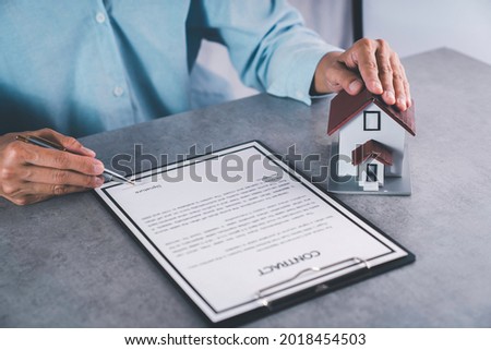 Real estate agent signing contract about the agreement of real property on the desk, house broker and planning investment, businessman writing on document form rent house, business concept.