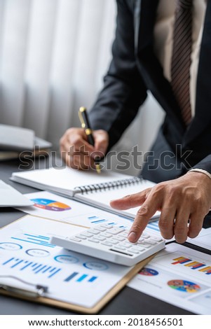 A male accountant or a business man uses a laptop to calculate investment results. And making financial reports on the desk Business finance accounting concept Royalty-Free Stock Photo #2018456501