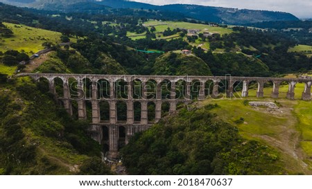 Arcos del Sitio in the Magical Town of Tepotzotlan, State of Mexico, the ocher colors of the arches quarry contrast with the green of the grass. Royalty-Free Stock Photo #2018470637