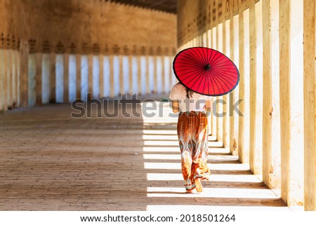 Young woman walking with umbrella in Shwezigon pagoda temple in Bagan. Myanmar.