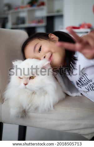 A girl takes a picture with her favorite white cat. Asian children hugging white cat.