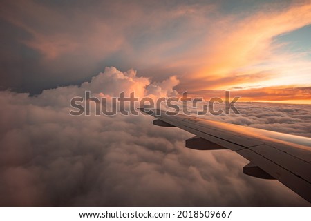 The view from the airplane window to the clouds and sunset. Airplane wing above thick pink and orange clouds. Wonderful breathtaking view. Royalty-Free Stock Photo #2018509667