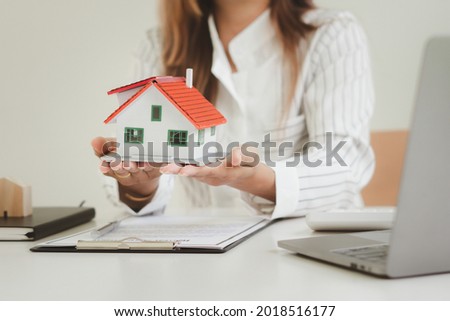 Female agent covering house model at table, closeup. Home insurance Royalty-Free Stock Photo #2018516177