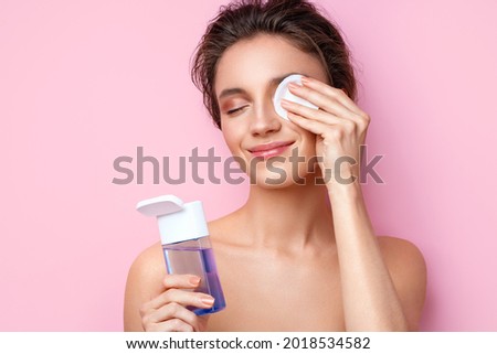 Woman removing makeup, holds cotton pads near face. Photo of woman with perfect skin on pink background. Beauty and skin care concept Royalty-Free Stock Photo #2018534582