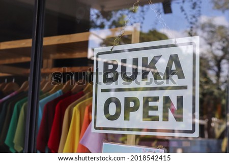 a hanging sign board with word buka means open inside glass window