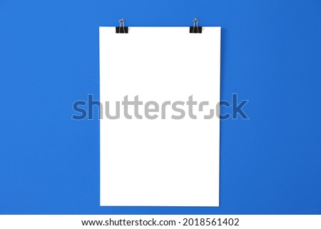Blank poster hanging on color wall