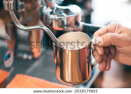 Barista is using high pressure steam operated milk frother to prepare a coffee milk. Royalty-Free Stock Photo #2018579801